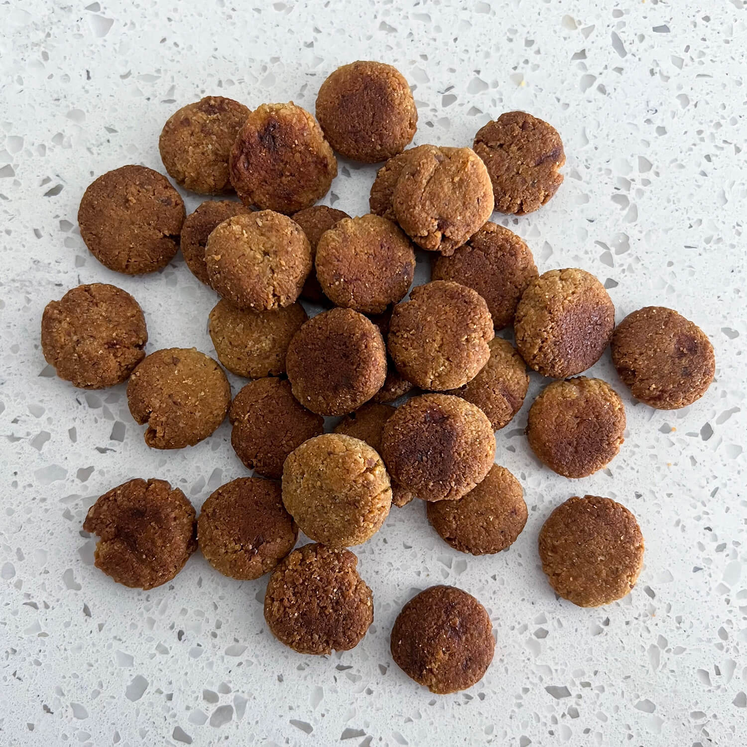 Image displaying Wagging Companions' 'PB & B' (peanut butter and banana) blend dog treats outside of their packaging. These treats consist of a wholesome combination including almond flour, banana, peanut butter, coconut oil, and turmeric. The blend showcases the brand's commitment to nutritious, plant-based ingredients tailored for dogs' health and enjoyment.