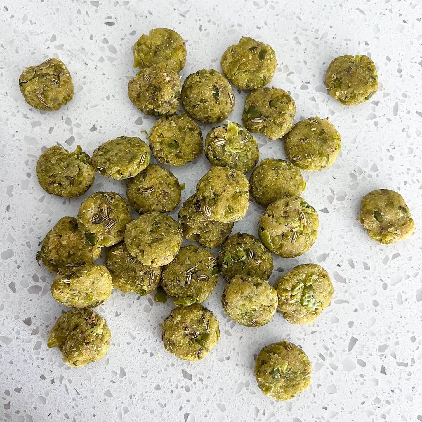 Image displaying Wagging Companions' 'Side Salad' blend dog treats outside of their packaging. These treats consist of a blend containing green peas, almond flour, parsley, fennel seeds, and flaxseed. The diverse mix reflects the brand's commitment to providing a nutritious, plant-based option tailored for dogs' health and well-being.